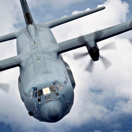 Close cropped shot of RAAF Hercules C130 flying against blue sky and cloud background